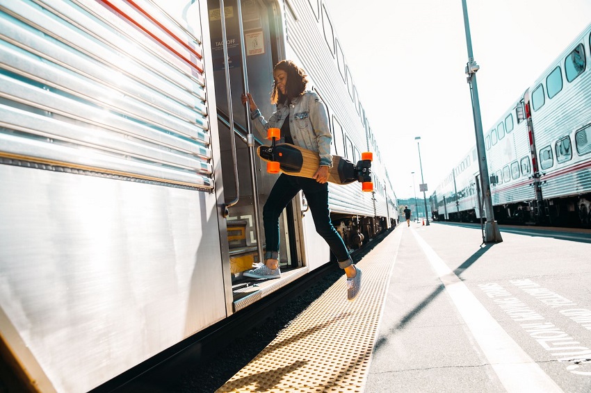 Girl getting on the train with boosted board