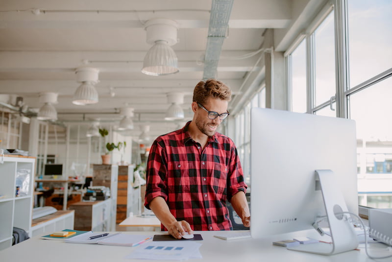 man smiling while working on a standing desk