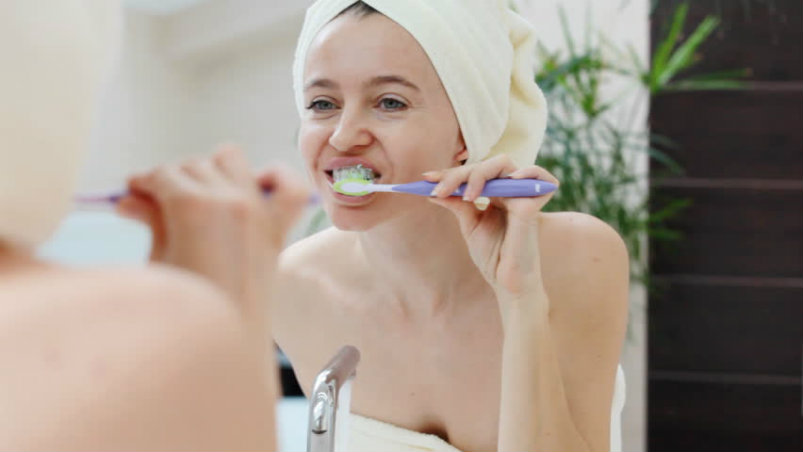 women brushing her teeth dental care