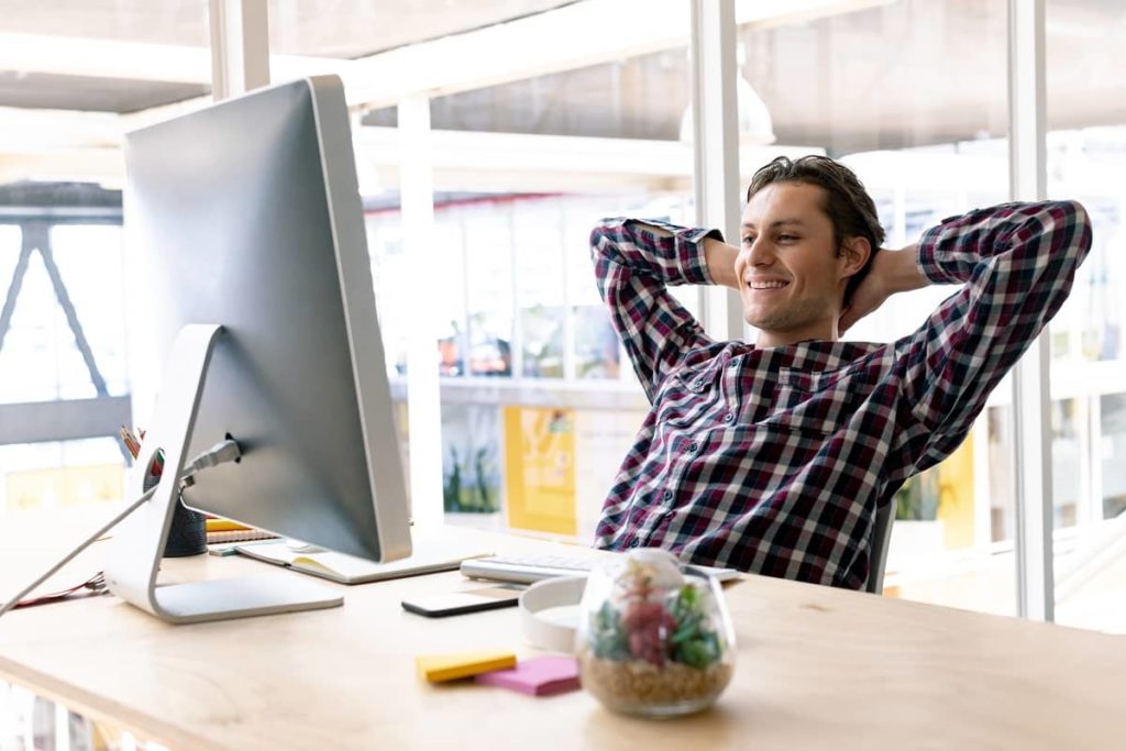 Caucasian male hands behind head sitting on chair in a modern office