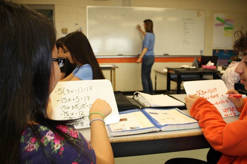 students writing on individual white boards