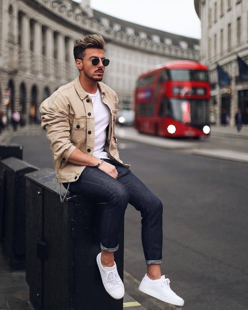 picture of a men sitting on a bench beside a street with a bus 