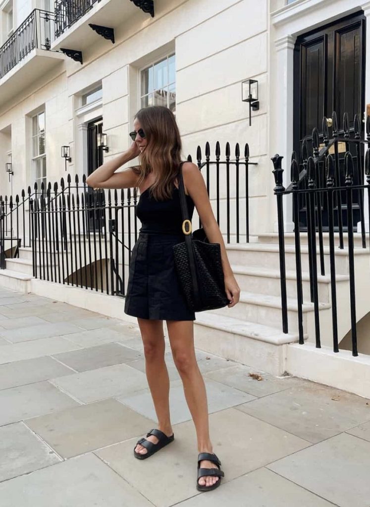 picture of a woman standing on a sidewalk wearing black outfit and brikenstock women's casual sandals