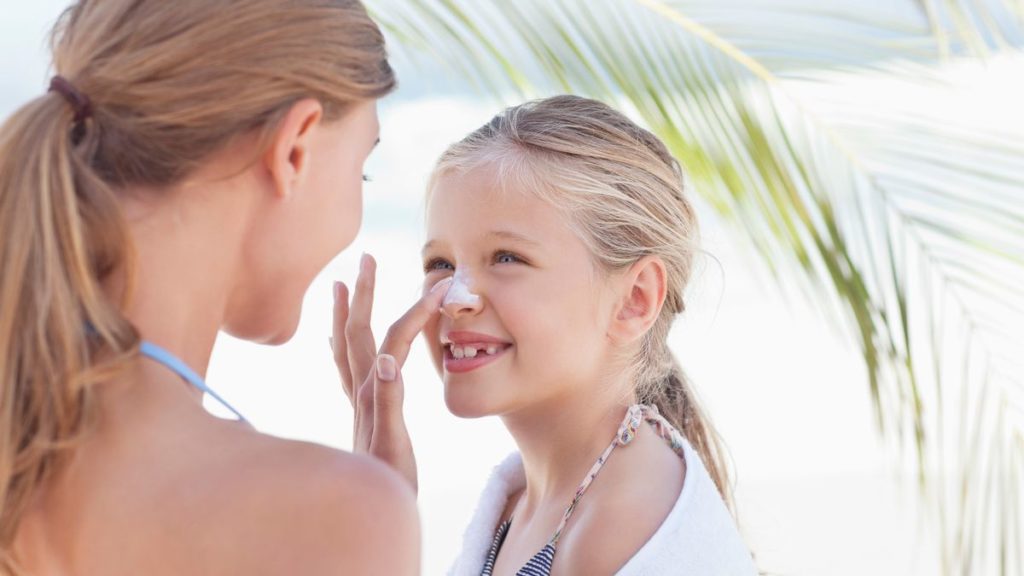 Mum putting sun screen on her daughter's face