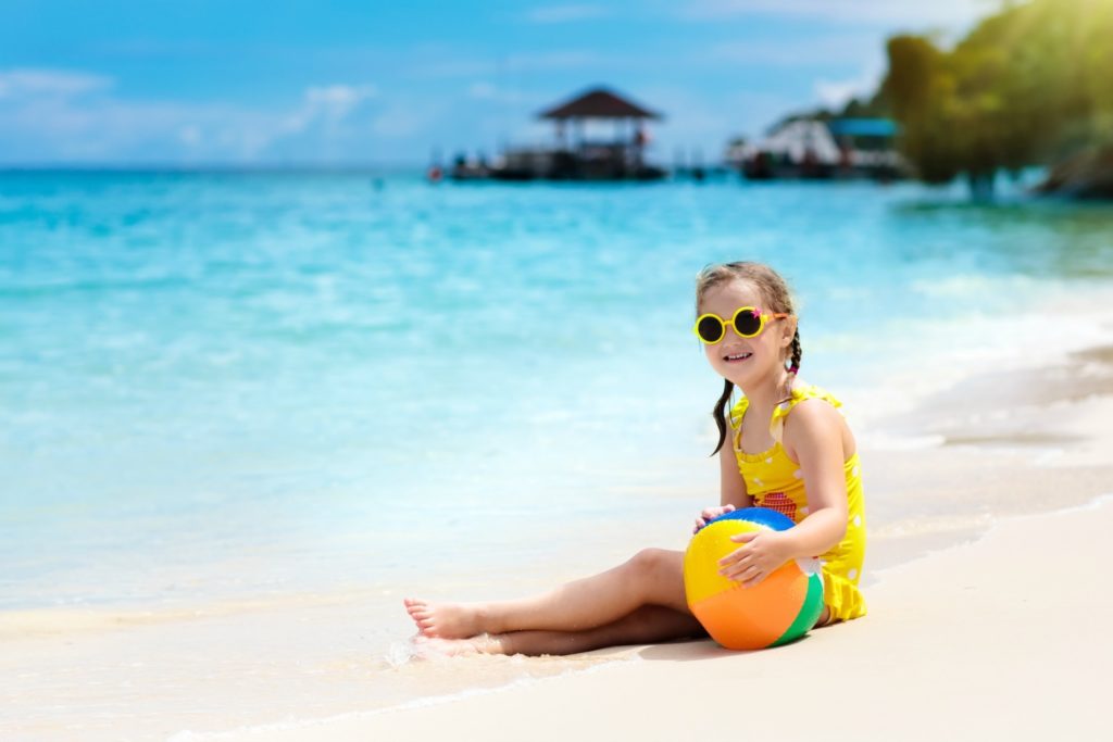 Child playing ball on tropical beach. Little girl at sea shore. Family summer vacation. Kids play with water and sand toys. Ocean and island fun. Travel with young children. Asia holiday.