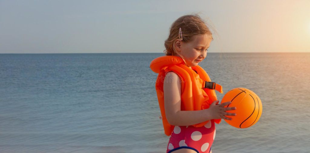 Happy blonde girl at the beach with swim vest